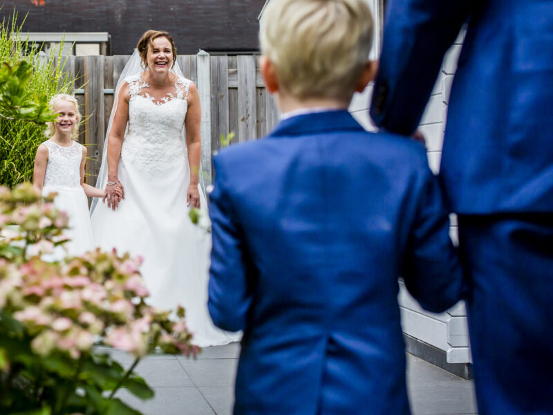 Bruid en bruidsmeisje zien bruidegom en bruidsjonker aankomen. Fotograaf Karin Keesmaat van Kijk-Kunst fotografie