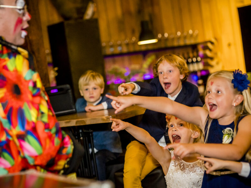 Kinderen op bruiloft wijzen naar clown/goochelaar. Fotograaf Karin Keesmaat van Kijk-Kunst fotografie